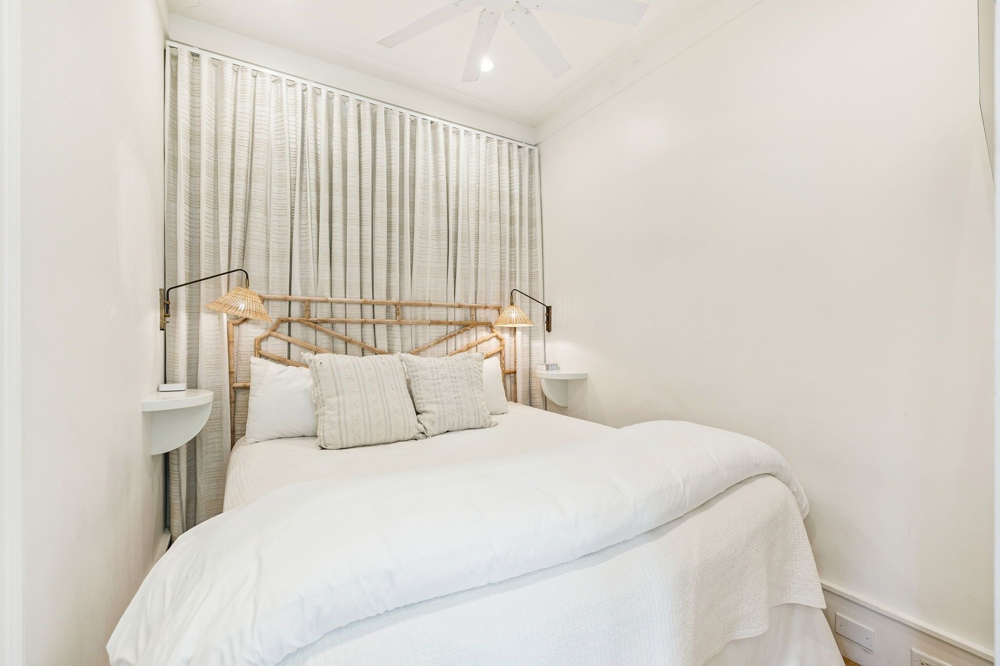 A neatly arranged bedroom with a bed, two bedside tables, and a headboard with a woven design.