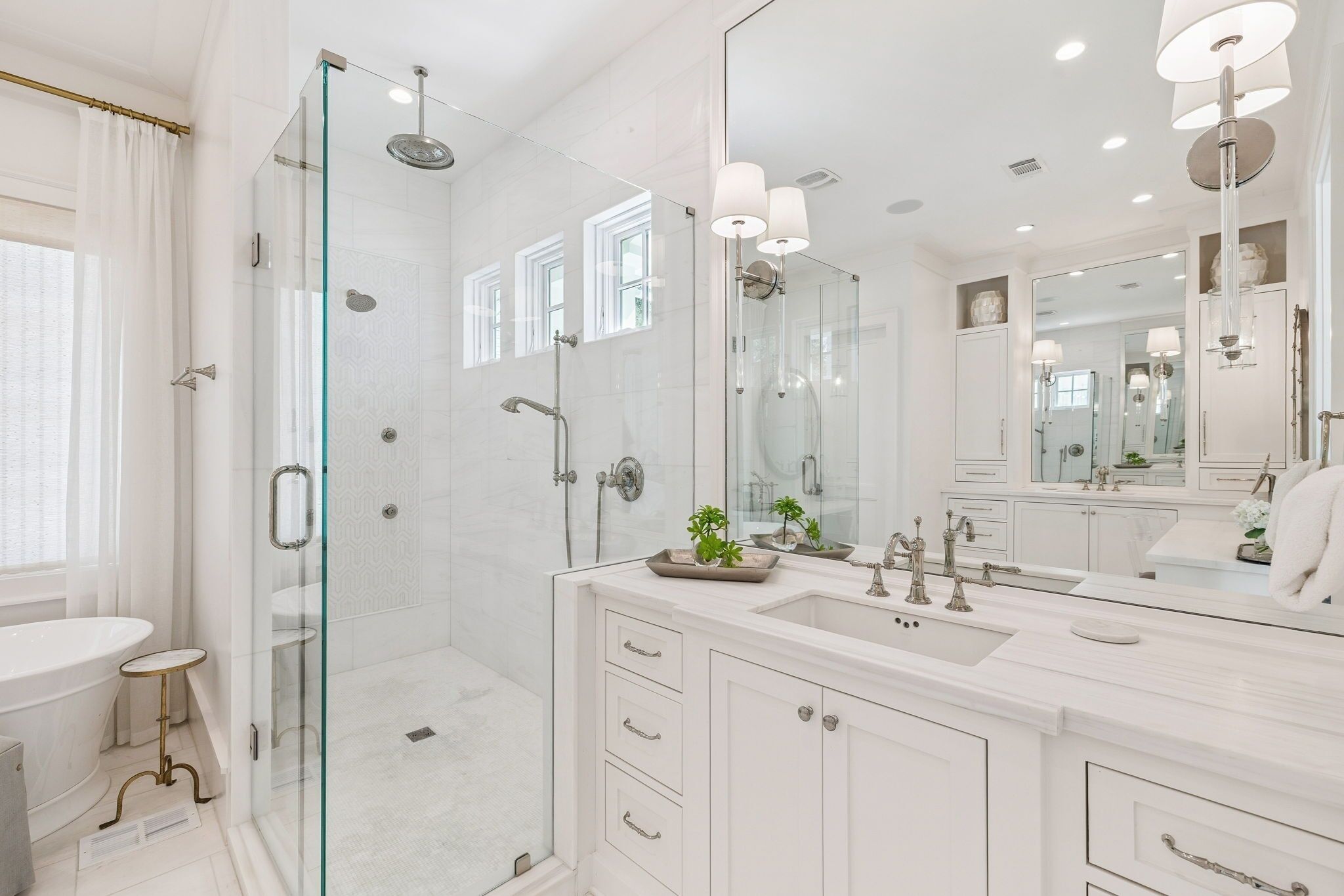 A modern bathroom with a glass-enclosed shower, a large mirror, and a vanity with a sink.