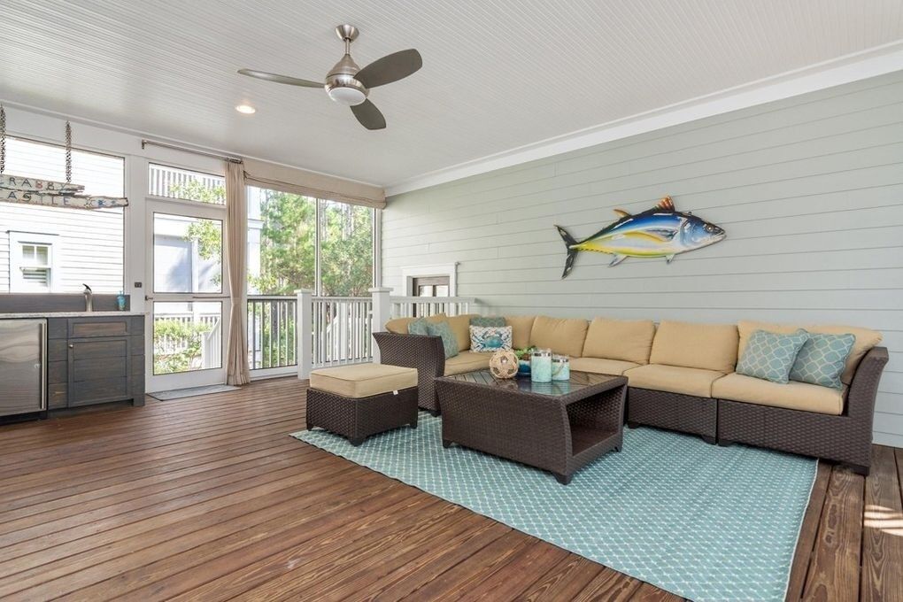 A spacious living area with a large sofa, two armchairs, and a coffee table. A ceiling fan is visible, and a fish mural adorns the wall.