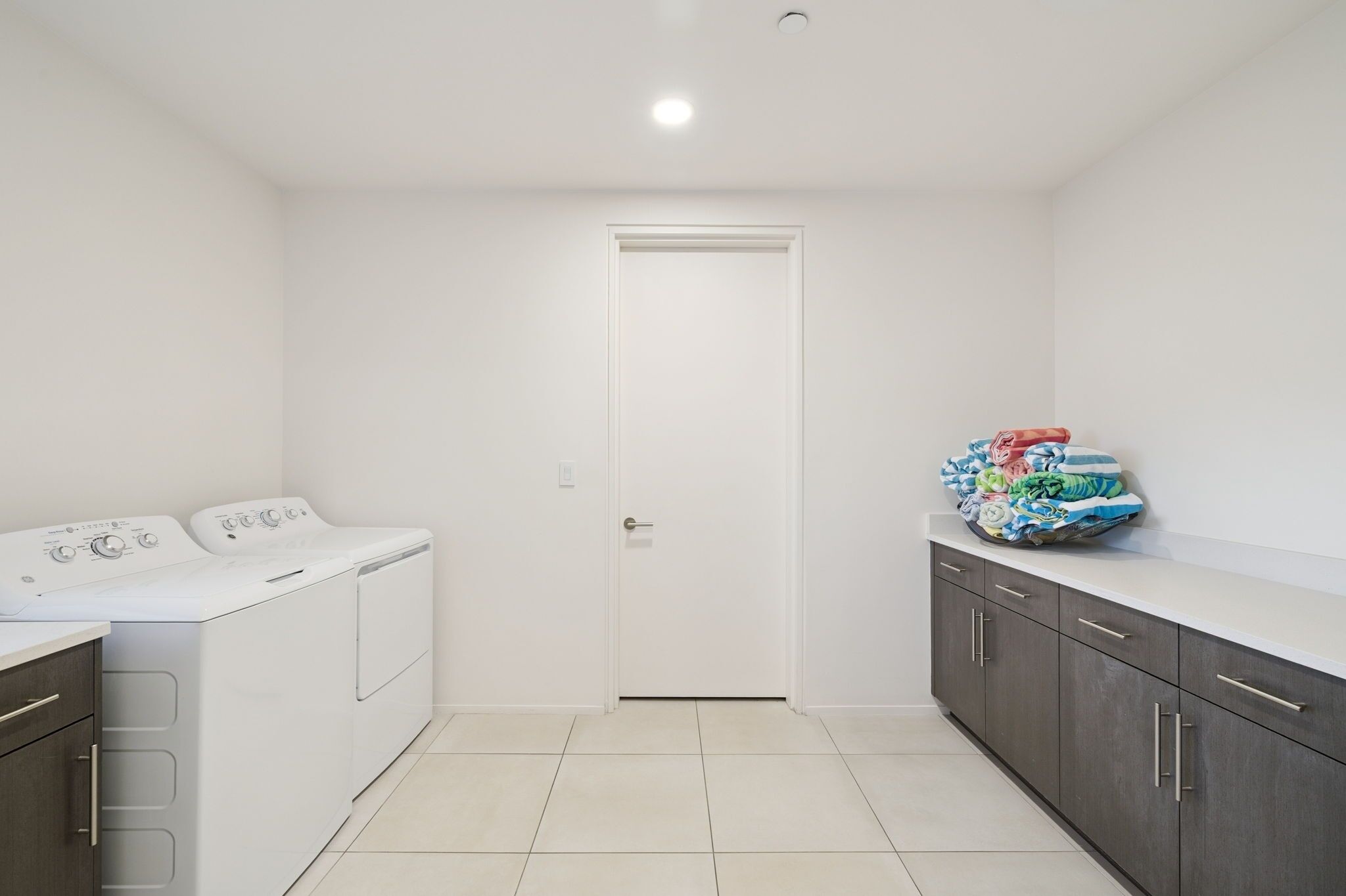 A laundry room with a washing machine, dryer, and a cabinet with folded clothes.