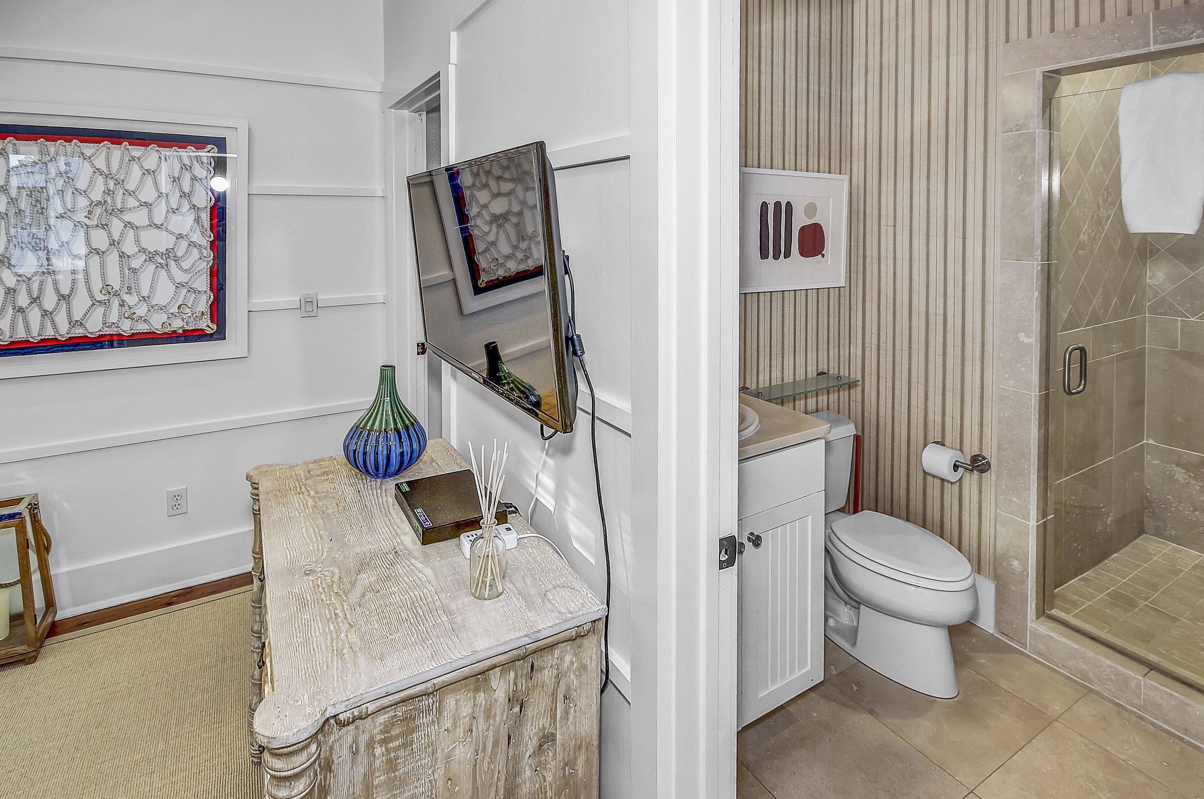 A bathroom with a toilet, a shower, and a vanity with a mirror.