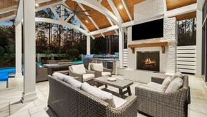 An outdoor patio with wicker furniture, a stone fireplace, and a pool. - 'mirasol House' Pool + Golf Cart Watercolor, Fl 4br/4ba/bonus Bunk -- Sleeps 12 4 Bedroom Home by RedAwning (Santa Rosa Beach)