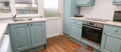 Una cuina moderna amb armaris blau cel, un forn d'acer inoxidable i una finestra amb vista a l'exterior.