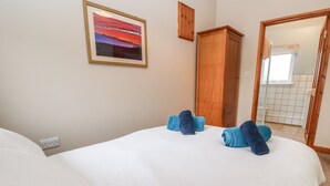Et hotelværelse med en seng, et træskab, et billede på væggen og et badeværelse, der kan ses gennem en åben dør.