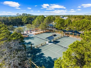 A tennis court surrounded by trees and a gazebo.