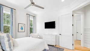 A bedroom with a bed, a dresser, a television, and a door leading to another room. - Private Pool And Close To Sandhill Pool - Watercolor Lake District Home 4 Bedroom Home by RedAwning (Santa Rosa Beach)