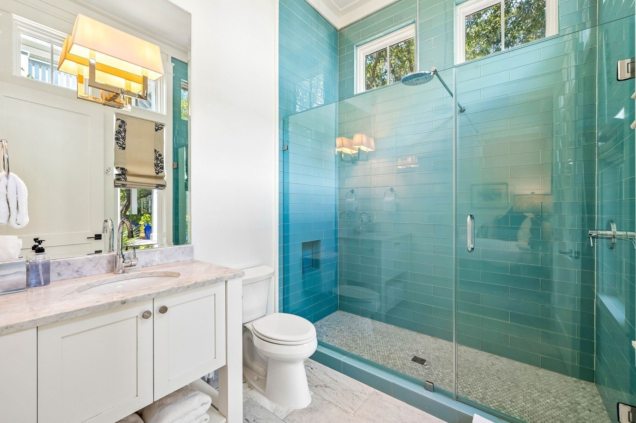 A bathroom with a glass-enclosed shower, a white toilet, and a marble countertop.