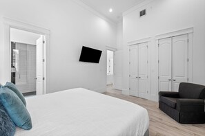 Een slaapkamer met een bed, een aan de muur bevestigde televisie en een kledingkast.