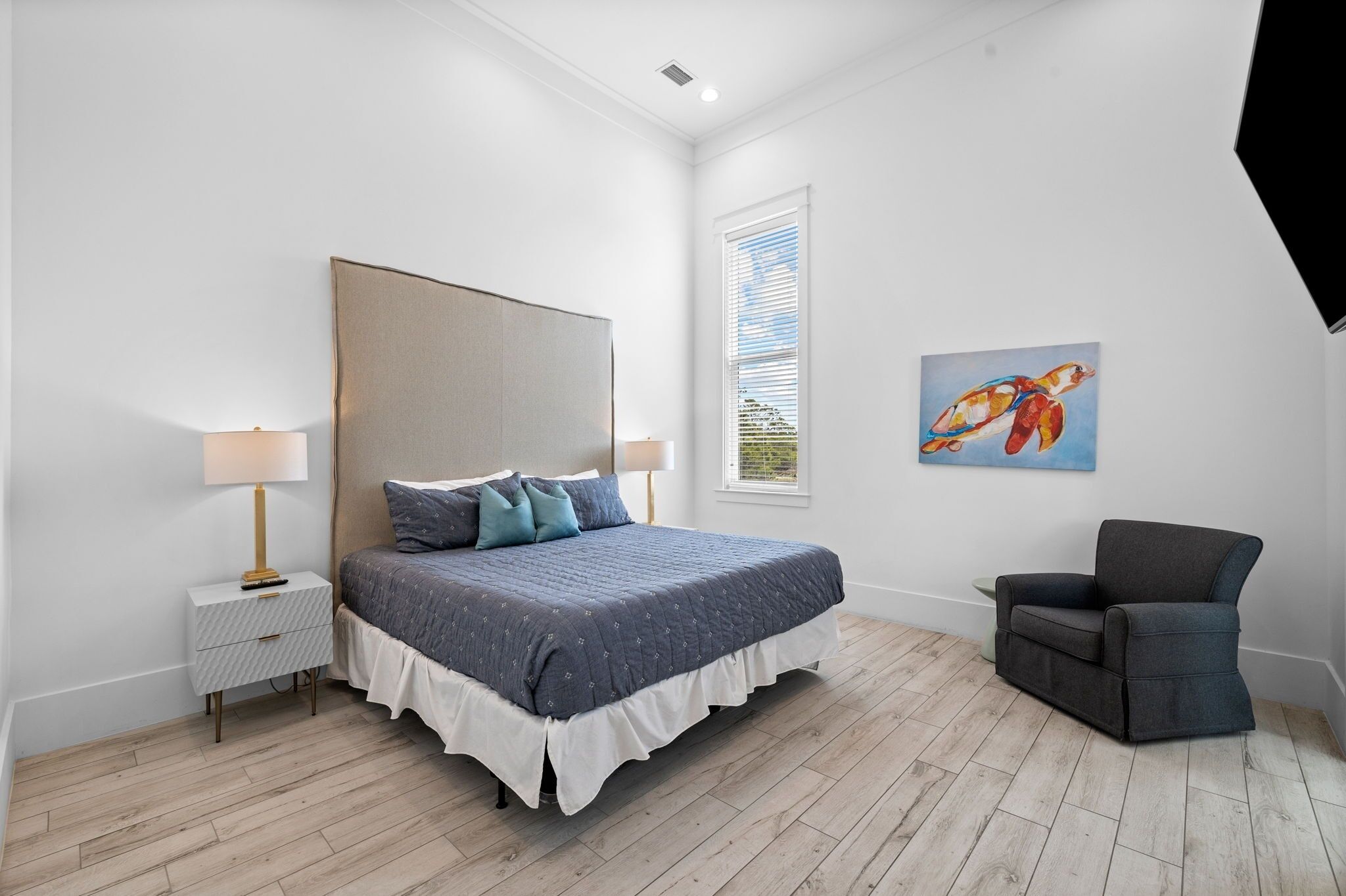 Une chambre à coucher avec un lit, des tables de chevet, une chaise et une fenêtre avec des stores.