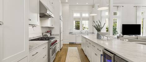 A modern kitchen with white cabinetry, a central island, and pendant lighting.
