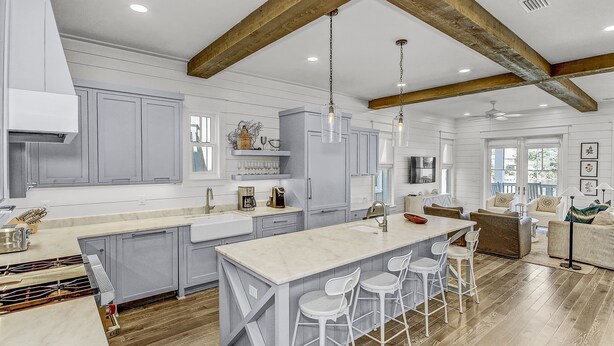 A spacious kitchen with a large island, wooden beams, and a dining area with a sofa and chairs.
