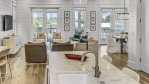 A spacious kitchen with a large island, white cabinetry, and a dining area with chairs and a table.