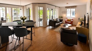 Un soggiorno moderno con zona pranzo, ampie finestre e vista sull'esterno.