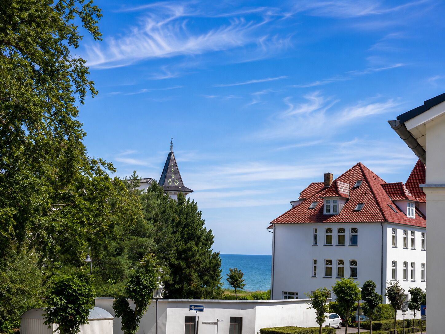 A coastal town with a church steeple, white buildings, and a clear blue sky.