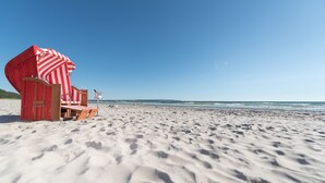 Una spiaggia con una sedia a sdraio a righe rosse e bianche e un lettino di legno.