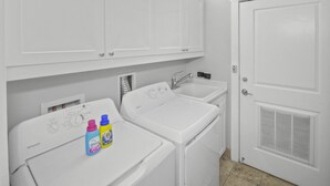 A laundry room with two white washing machines, a sink, and a door with a vent. - amazing Gulf Views 420b Watersound Crossings 3br, Corner Unit 3 Bedroom Condo by RedAwning (Santa Rosa Beach)