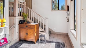 A hallway with a wooden cabinet, a small stool, a rug, and a window with a view of trees. - Serene Forest-Front Retreat: 4BR Rocky Ridge Gem (Tahoe City)