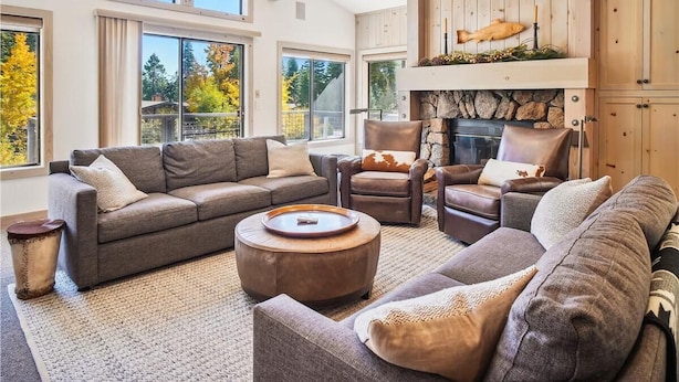 A spacious living room with a fireplace, large windows, and a high ceiling. - Serene Forest-Front Retreat: 4BR Rocky Ridge Gem (Tahoe City)