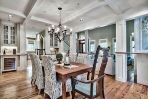 A dining room with a wooden table, patterned chairs, and a chandelier. - 'serendipity' Beautiful 3br Cottage Sleeps 8 close To Lazy River/pool At Camp Watercolor 3 Bedroom Home by RedAwning (Santa Rosa Beach)