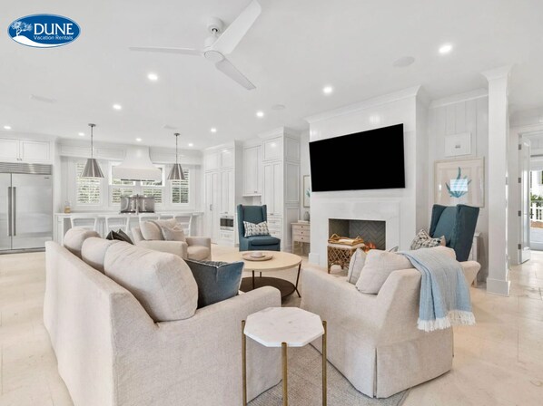 A modern living room with a sofa, armchairs, a coffee table, and a fireplace. - Newly Designed Custom Seaside Home with 6 Bedrooms + Next to Adult Pool/Fitness Center 6 Home by RedAwning (Santa Rosa Beach)