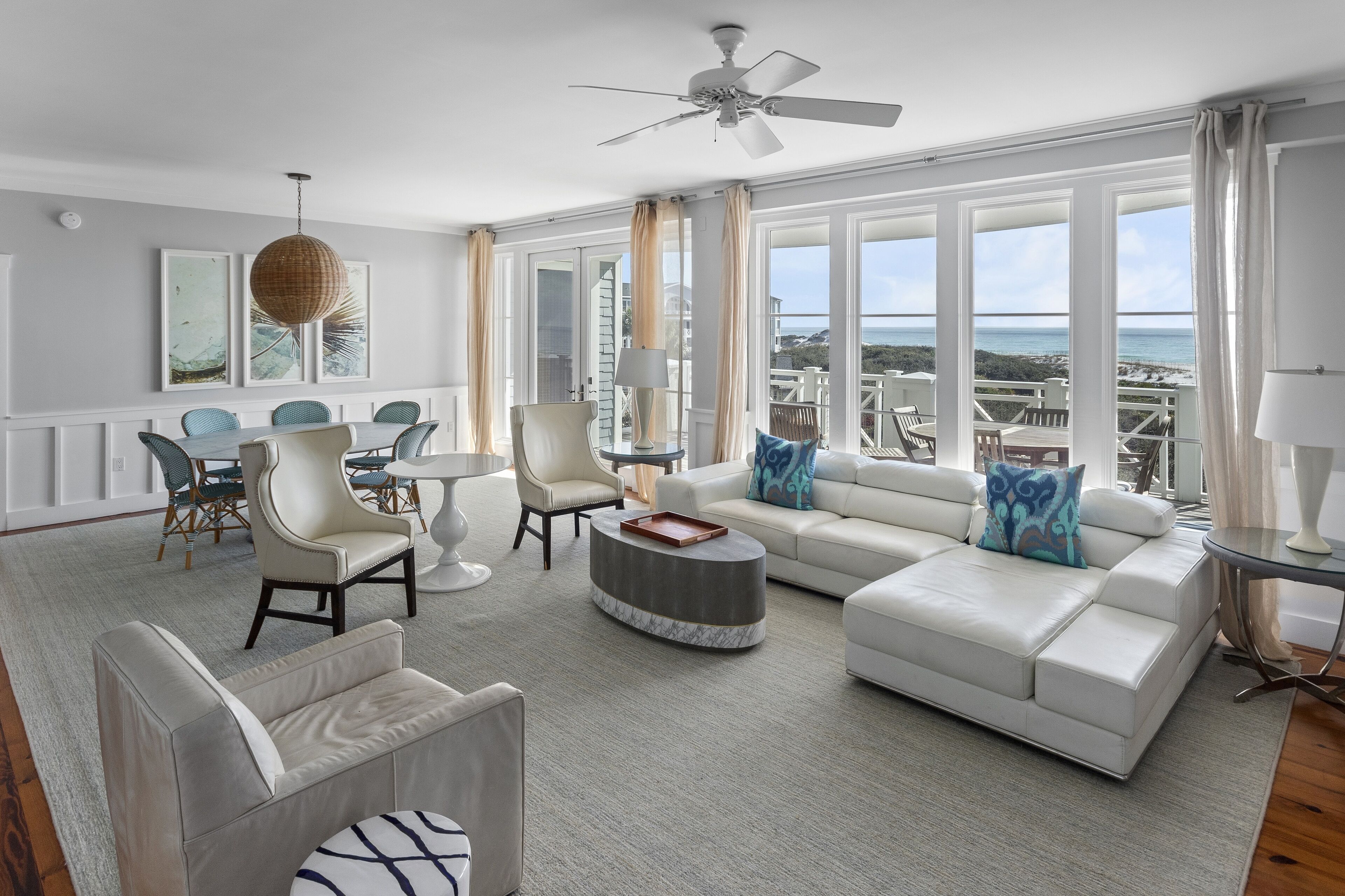 A spacious living room with a white sofa, round coffee table, and a dining area with chairs and a table.