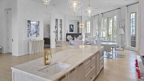 A modern kitchen with a marble countertop, gold faucets, and pendant lighting. - Private Pool, Gulf Views + Luxurious Features Throughout This Lovely Residence 6 Bedroom Condo by RedAwning (Panama City Beach)