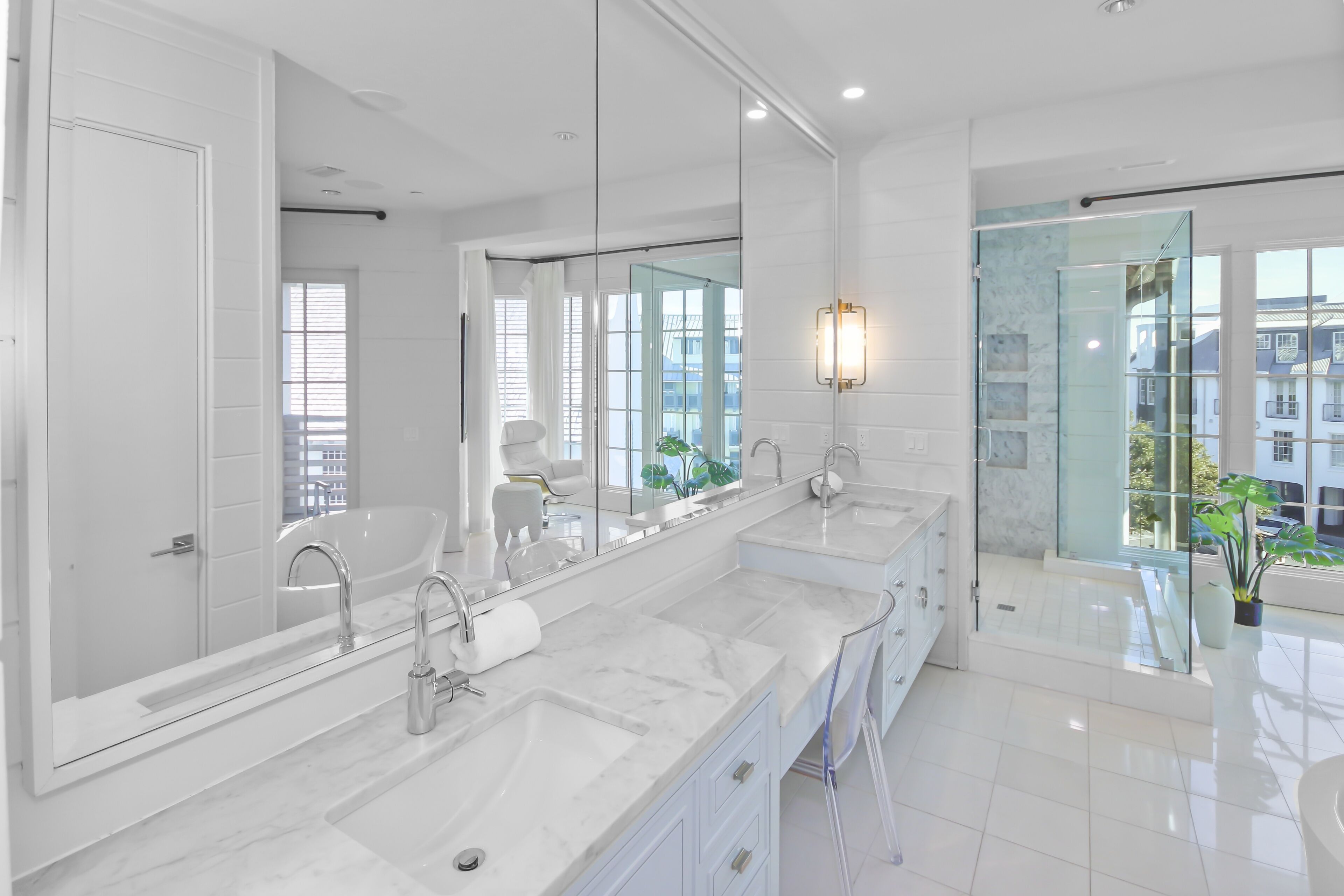 A modern bathroom with a large mirror, two sinks, a bathtub, and a glass-enclosed shower.