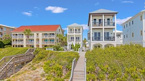 A coastal hotel with multiple balconies, a wooden boardwalk, and lush vegetation. - Shellstone Cottage Beach Front Seacrest Home with Private Pool and 5 Bedrooms 4 Home by RedAwning (Panama City Beach)
