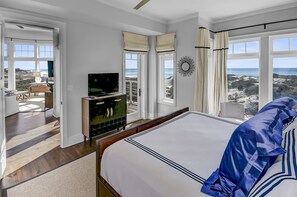 A bedroom with a large bed, a television, and a view of the ocean. - Gulf Front Penthouse Condo Complimentary Golf Cart 407 Compass Point 1, Watersound - 3 Br, Slps 8 3 Bedroom Condo by RedAwning (Santa Rosa Beach)