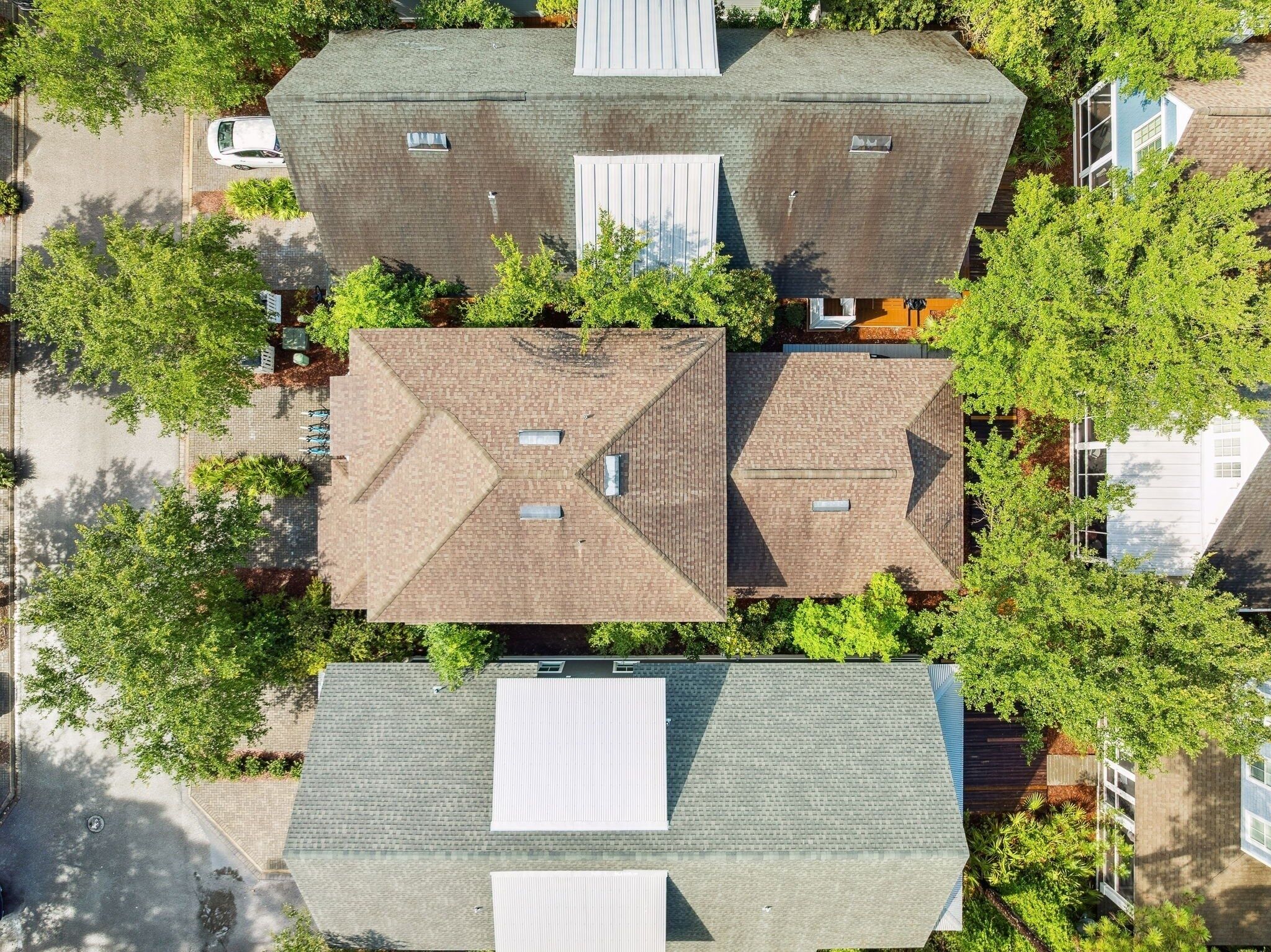 An aerial view of a residential area with multiple houses, each featuring distinct roof designs and surrounded by greenery.