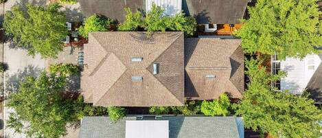 An aerial view of a residential area with multiple houses, each featuring distinct roof designs and surrounded by greenery.