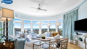 A spacious living room with a large window offering a scenic view, a ceiling fan, and a flat-screen TV. - GULF VIEWS from ALL Bedrooms! 308 Compass Point 1 in WaterSound Short walk to the beach and pool 3 Condo by RedAwning (Santa Rosa Beach)