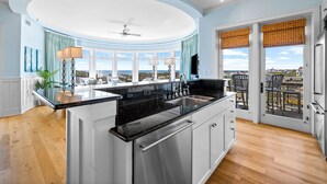 A modern kitchen with a central island, large windows, and a view of the city. - GULF VIEWS from ALL Bedrooms! 308 Compass Point 1 in WaterSound Short walk to the beach and pool 3 Condo by RedAwning (Santa Rosa Beach)