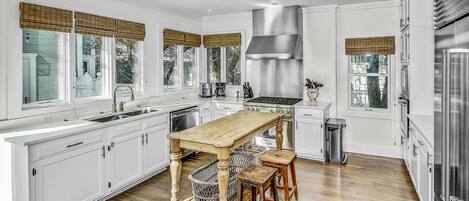 Una cocina moderna con armarios blancos, una isla de madera y una campana extractora de acero inoxidable.