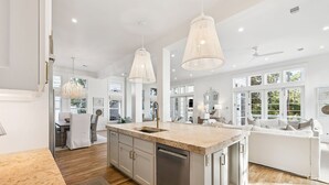 A modern kitchen with a central island, pendant lights, and a view to the dining area. - Private Pool, Lake Views, Great Outdoor Space Lake District Home In Watercolor, Fl 6 Bedroom Home by RedAwning (Santa Rosa Beach)