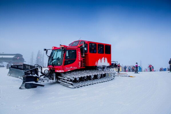 A red snowmobile with tracks, surrounded by snow and a clear blue sky.