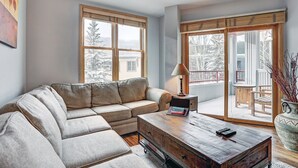 Una sala de estar con un sofá modular, una mesa de centro y vistas a un paisaje nevado a través de amplios ventanales.