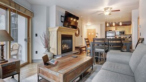 Una sala de estar con chimenea, televisor y comedor con sillas y una mesa.