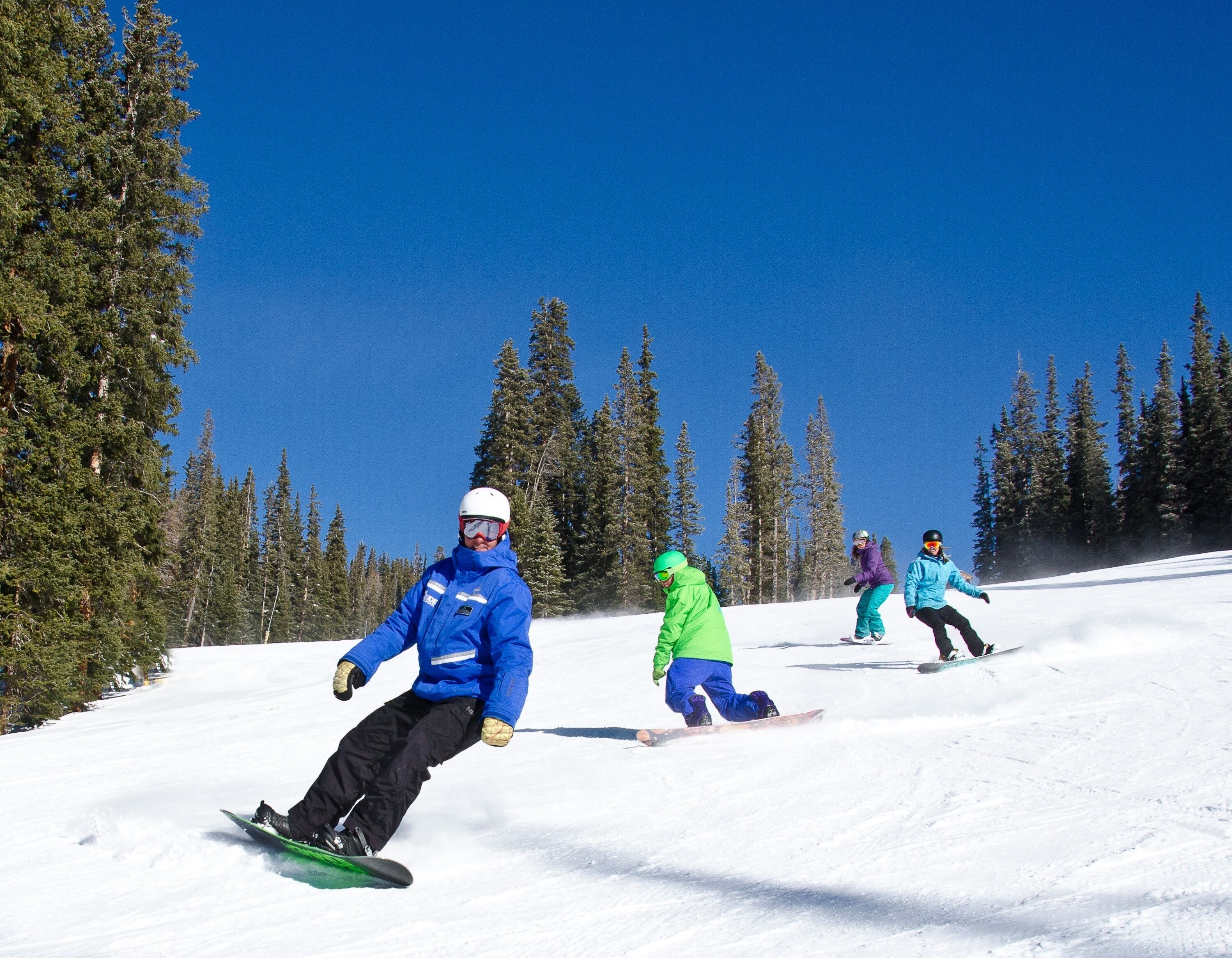 A group of people snowboarding on a clear day.