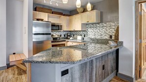 Una cocina moderna con encimeras de granito, electrodomésticos de acero inoxidable y armarios de madera.