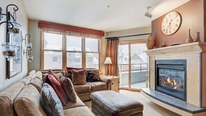 A cozy living room with a fireplace, a sofa set, and a large window with curtains. - Silver Mill 8253-1br-walk To Slopes! Kids Ski Free! 1 Bedroom Condo by RedAwning (Keystone)