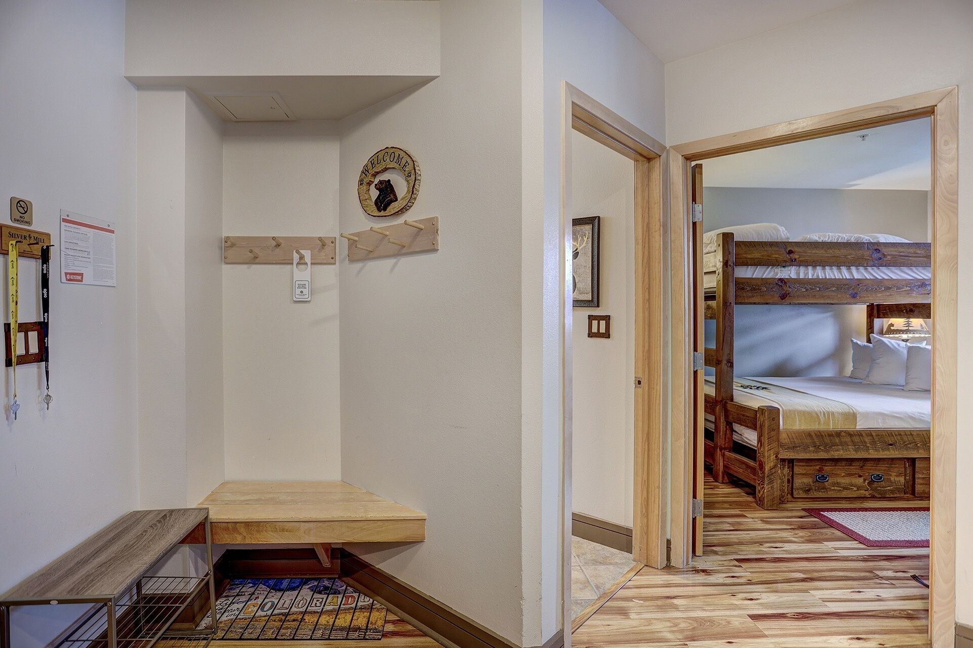 A hallway leading to a room with a bunk bed, a welcome sign, and a no smoking sign.