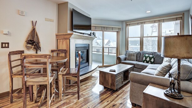 A living room with a fireplace, wooden furniture, a sofa, and a TV mounted on the wall.