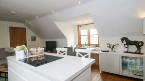 Eine moderne Küche mit Kochinsel, weißen Schränken und einem Essbereich mit Fenster.