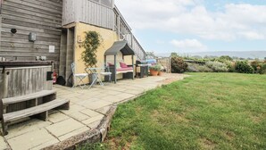 Ein Holzhaus mit einer Terrassenanlage, Sitzgelegenheiten im Freien und einem Rasen.
