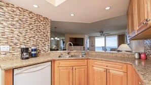 Una cocina moderna con encimera de granito, armarios de madera, lavavajillas y salpicadero con mosaicos.