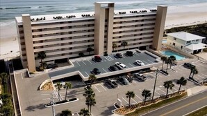 Un hotel de varios pisos con estacionamiento, piscina y vista al mar.