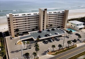 A multi-story hotel with a parking lot, a pool, and a beach view. - Beautiful 2 bedroom 2 bath oceanfront on traffic free beach at 207 South Point (Ponce Inlet)