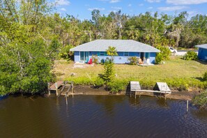 Situated on a grassy area with a dock, this single-story house offers a serene lakeside retreat.