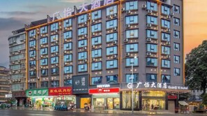 A multi-story hotel with a modern facade, multiple balconies, and a variety of storefronts on the ground level. - Guangyi Hotel (Quanzhou)